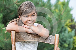Cool little girl is leaning on an vintage wooden chair