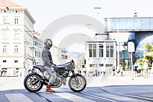 Cool looking motorcycle rider on custom made scrambler style cafe racer photo