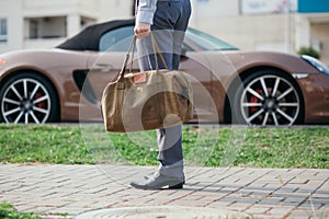 Cool man beautiful model outdoors, city style fashion. A handsome man model walking in the city center next to some cars