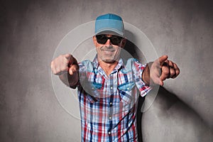 Cool mature casual man with trucker hat pointing his fingers