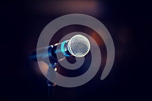 Cool mic on a stand in front of the concert hall, beautiful blurred dark background with a copy space for a message.