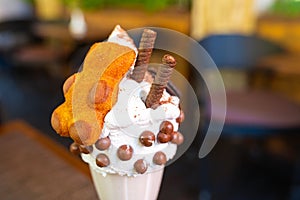 Cool milkshake with cookies and chocolate balls. Milkshake in a glass beaker on a table on a street platform in a cafe. Refreshing