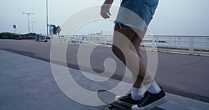 Cool millennial woman skateboarding at beach