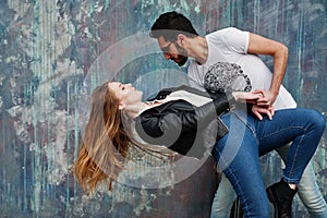 Cool multiracial couple posing against wall and dancing