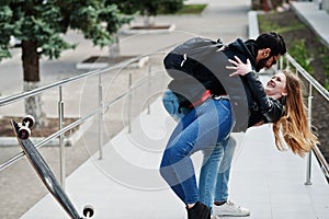 Cool multiracial couple posing with longboard and hugs together