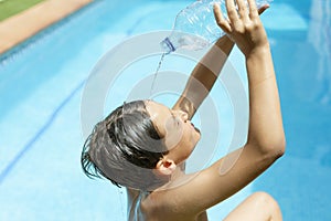 Cool off in the summer heat wave in the pool. young man splashing a bottle of water on his face. Concept of high temperatures in