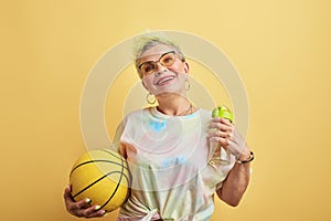 Cool old woman working out in the sport center with yellow wall