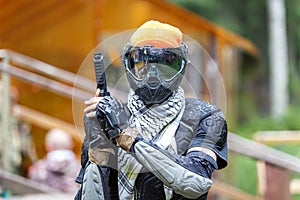 Cool paintball fighter in special armor holding paint handgun.