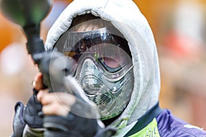 Cool paintball player with marker aiming in camera. Closeup.