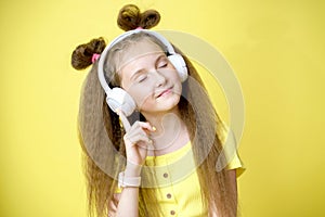 Cool pretty girl with trendy hairstyle in headphones listens to music on yellow background