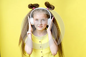 Cool pretty girl with trendy hairstyle in headphones listens to music on yellow background