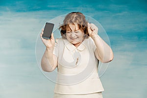 Cool red-haired plump woman in a white dress exults with a phone in her hands photo