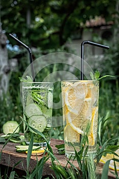 A cool, refreshing drink with lemon and cucumber on nature on a hot day