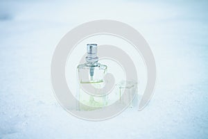 Cool refreshing fragrance of perfume in a glass bottle in the snow
