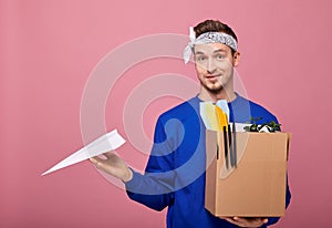 A cool retro guy in a white bandana with box and paper airplane in hands after being fired