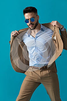 Cool retro young man in suit with sunglasses adjusting jacket