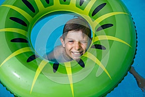 Cool school boy having fun on inflatable rubber circle in outdoor pool. Summer holiday. Summertime kids weekend. Child