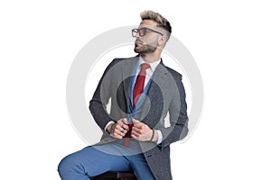 Cool sexy businessman fixing his coat, looking away