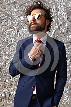 Cool sexy businessman fixing his tie, wearing sunglasses