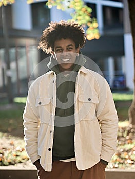 Cool smiling young African American guy standing at big city sunny street.