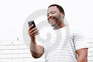 Cool smiling young black man looking at mobile phone