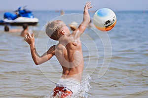 Cool sports boy jumping on the ball at sea
