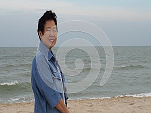 Cool stylish Asian senior woman smiling happy at beach nice fashion cloth