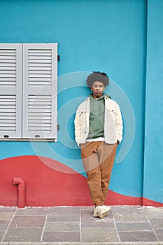 Cool stylish young gen z hipster African American guy at blue wall. Portrait