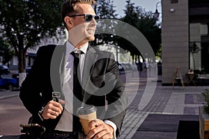 Cool successful ambitious businessman riding scooter outside office building, looking at side