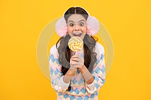 Cool teen child with lollipop over yellow isolated background. Sweet childhood life. Teen girl with yummy lollipop candy