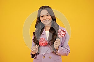 Cool teen child with lollipop over yellow isolated background. Sweet childhood life. Teen girl with yummy lollipop candy