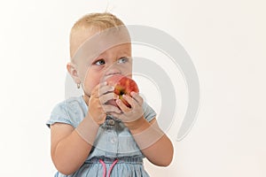 Cool toddler girl is eating red apple