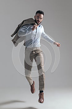 Cool unshaved businessman with glasses holding jacket over shoulder