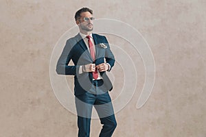 Cool unshaved businessman with sunglasses buttoning suit