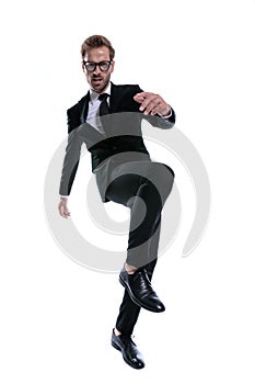 Cool unshaved man in black suit holding knee up