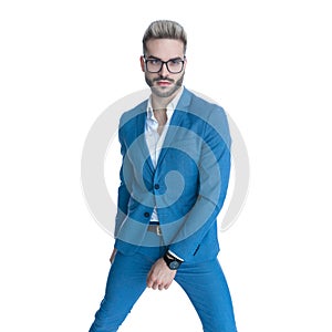 Cool unshaved man in elegant blue suit standing in a fashion position