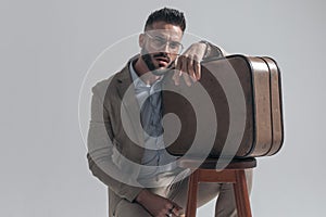 Cool unshaved model with glasses holding hand over briefcase