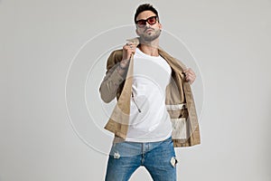 Cool unshaved young guy adjusting jacket and posing