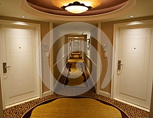 Cool view of a bright and empty corridor of a luxury hotel and closed doors.