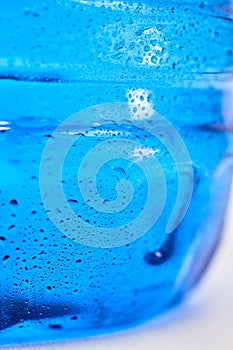 Cool water and water drops on a blue plastic bottle . Selective focus.