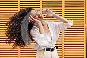 Cool young african girl waving her hair closed eyes smiling with teeth on yellow background.