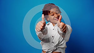 Cool young afro woman showing thumbs up, approves something, blue background