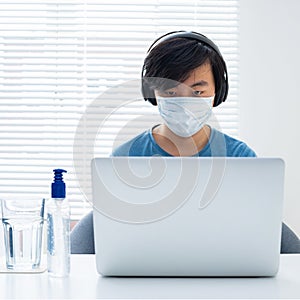 Cool young Asian boy doing homework on laptop computer