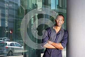 Cool young black guy leaning on wall and staring