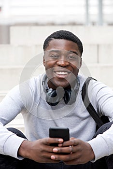 Cool young black man smiling with cellphone and headphones