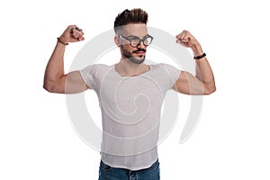 Cool young casual man flexing his bicceps muscles