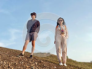 Cool young couple stands on the hill at sunset.