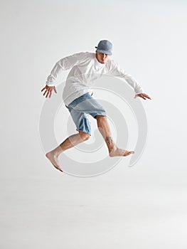 Cool young guy breakdancer jumps dancing hip-hop isolated on white background. Dance school poster. Break dance lessons