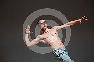 Cool young guy breakdancer in sunglasses dancing hip-hop without shirt in studio. Dance school poster