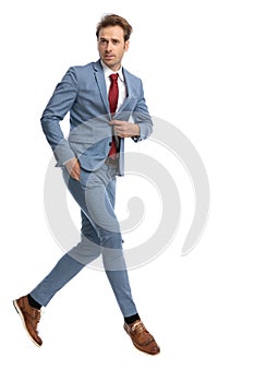 Cool young guy holding hand in pocket and unbuttoning blue suit